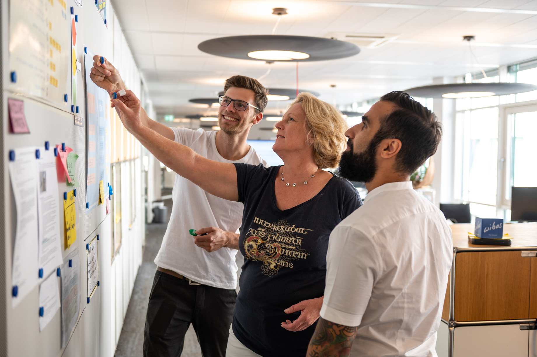 A group of 3 people jointly prioritizes tasks on a board.