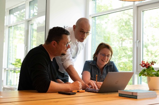 ART Coaching: Three people are together at a table looking at a laptop screen.