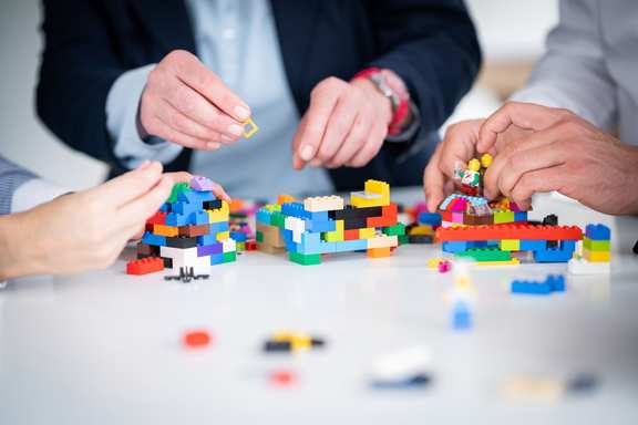 Das Bild zeigt ein Design Thinking Team, das mit Lego einen Prototypen baut.