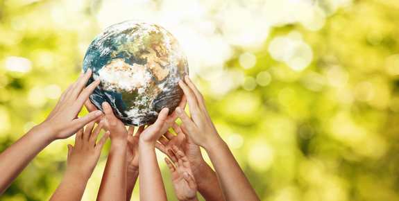 Many hands hold up globe