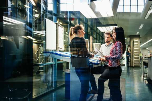 A team in an agile company standing together at a work table in a production hall