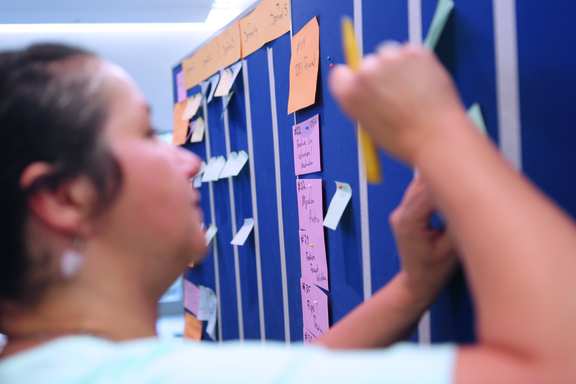 A woman works on a Kanban board and plans the implementation of a requirement