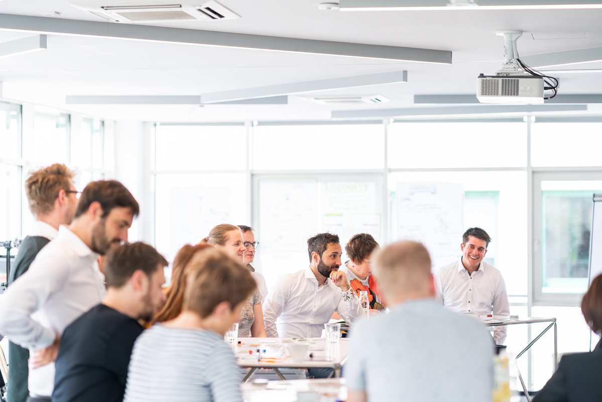 a large training group stands together in a relaxed atmosphere and laughs