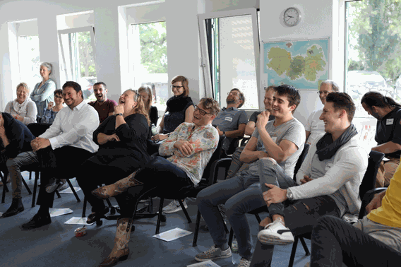 lachendes Plenum bei einer Firmenveranstaltung im Büro