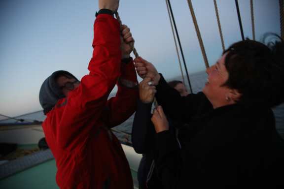 3 people hoist a sail