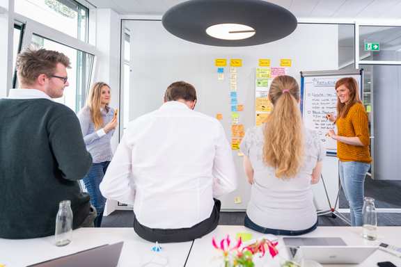 ein Team von 5 Leuten plant mit Post-its an einer Planungswand nächste Arbeitsschritte
