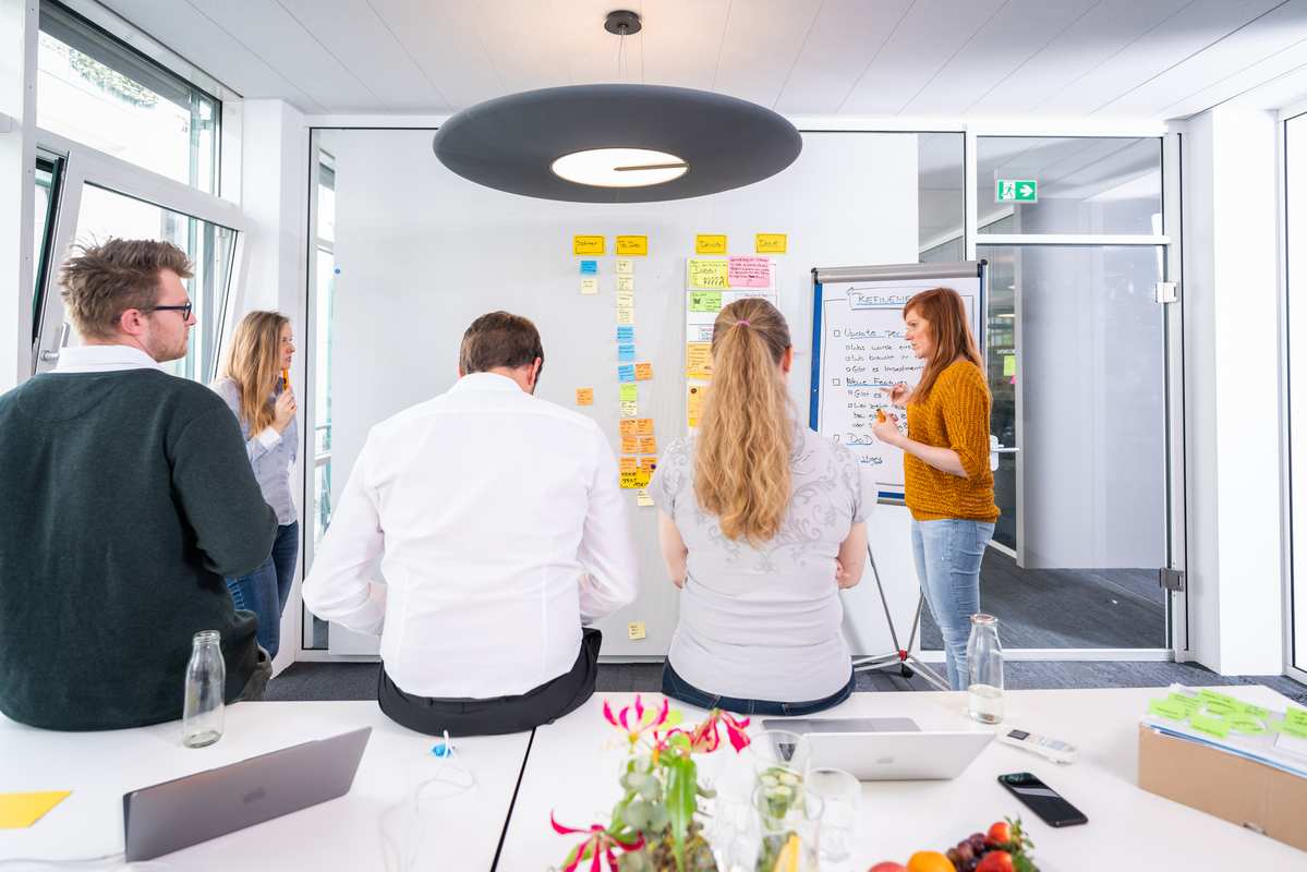 ein Team aus 5 Leuten plant nächste Arbeitschritte an einer Planungswand