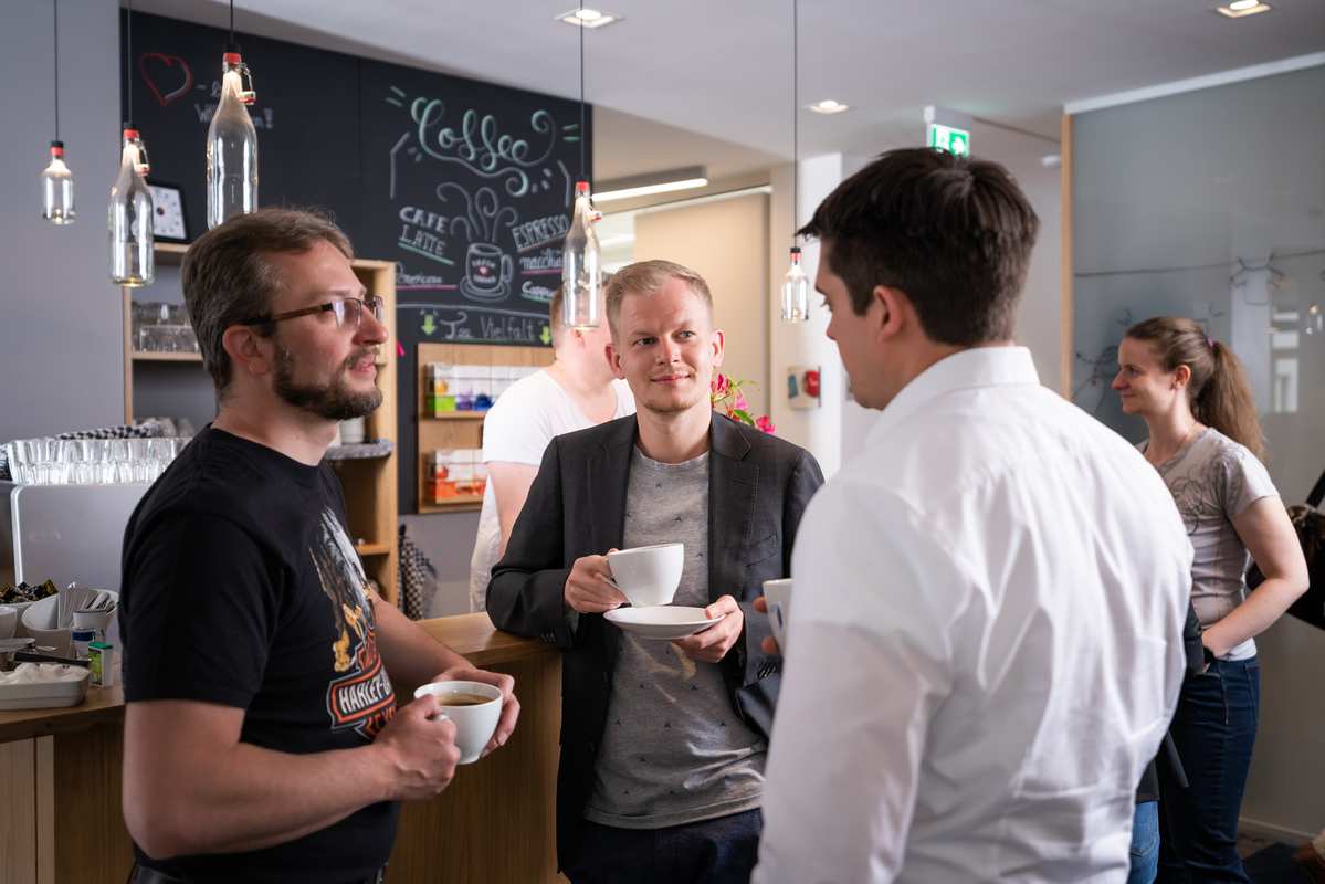 3 Menschen im Gespräch an einer Kaffeetheke