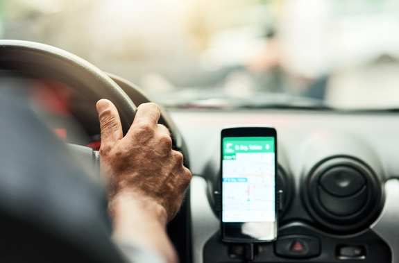 Nahaufnahme eines Mannes, der sein Smartphone zur Navigation beim Autofahren nutzt