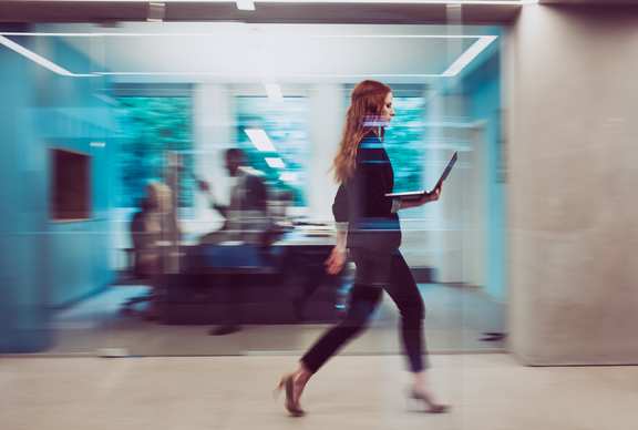 Frau läuft mit Laptop durch Büro