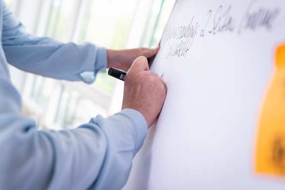 A hand writes on a plipchart