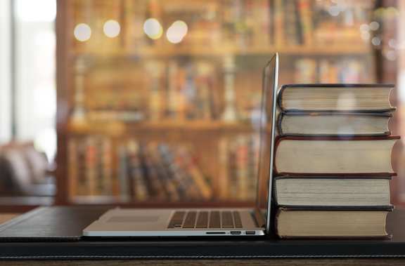 Laptop in front of a stack of books about law