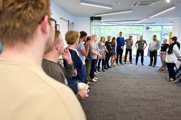 A large group of people stand in a circle and start the day together
