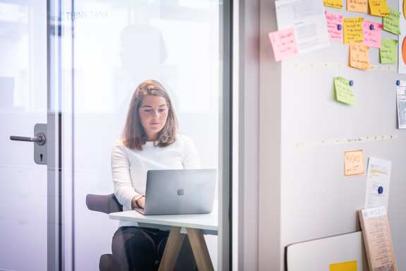 Employee Caroline works in the office (she is seen through a glass pane)